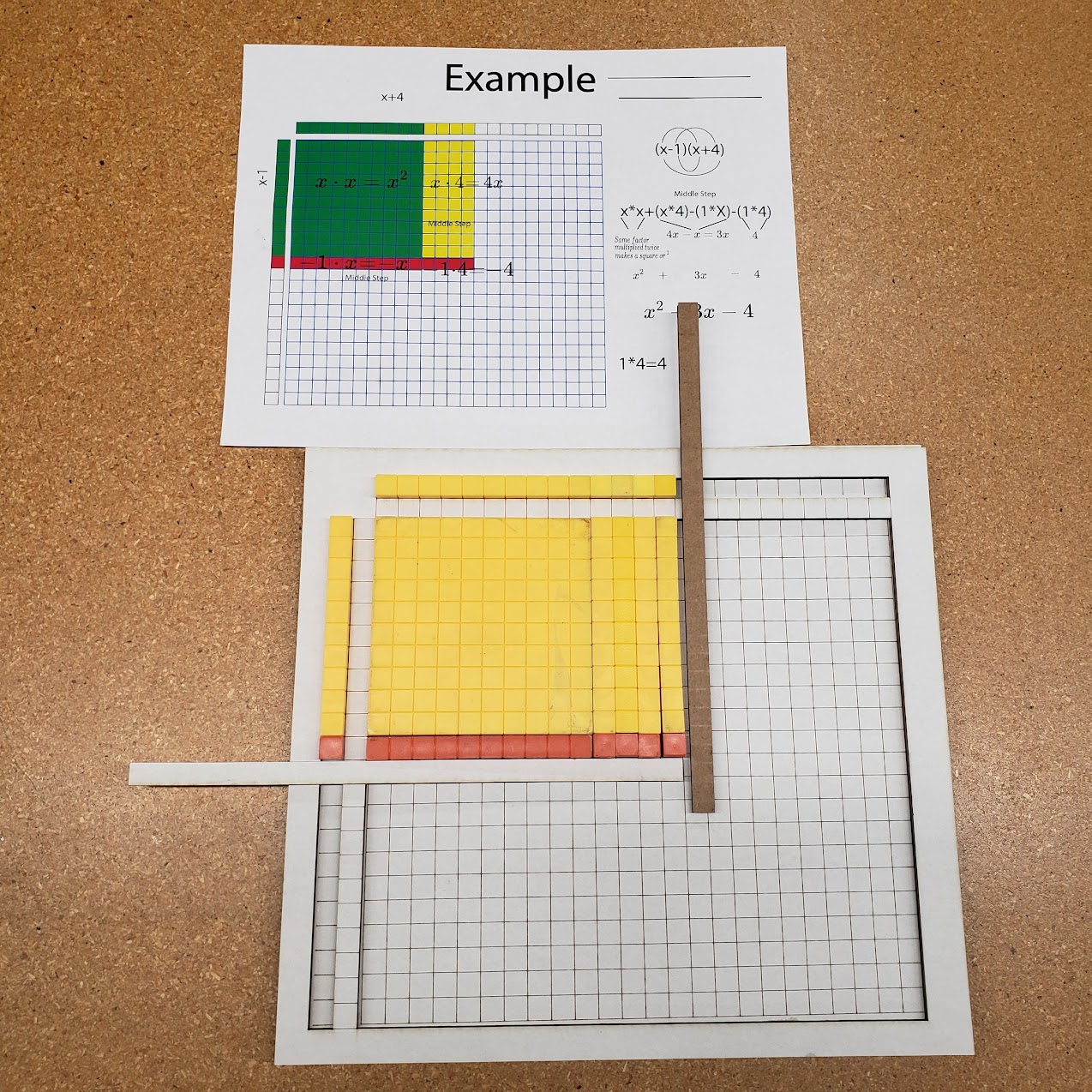 Physical algebra tiles manipulative board with base-ten blocks arranged on a grid to model polynomial multiplication